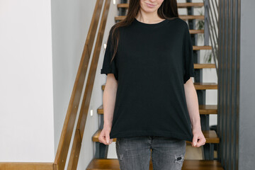 Woman wearing black blank t-shirt with space for your logo, mock up or design indoors