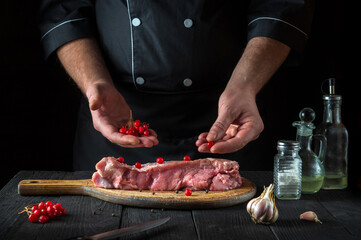 In the restaurant kitchen chef prepares raw calf meat. Before baking, the cook puts the viburnum on the beef. National dish