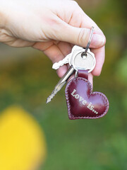 brown leather key trinket heart shape close up photo in human hands 