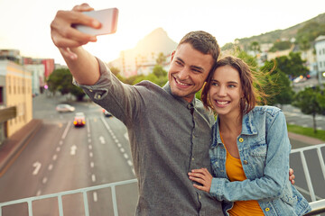 Naklejka premium Sentimental selfies. Shot of a happy young couple taking a selfie together in the city.