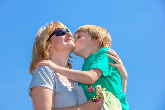 mother hugging her little son against the blue sky