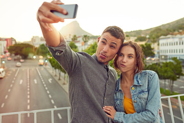 Lets get weird. Shot of a happy young couple taking a selfie together in the city.