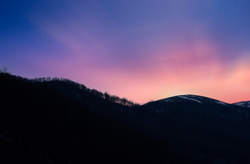 Sunset over the silhouette mountains.