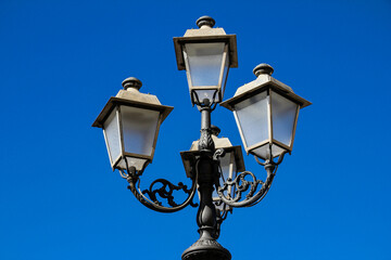 detail of three-headed street lamp with blue sky at the bottom