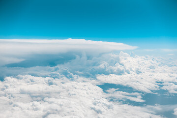 White puffy clouds taken from a moving airplane. Blue skies above. Flying in air. Plane ride travel. High quality photo