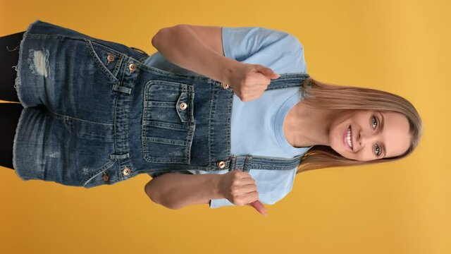 VERTICAL VIDEO POV smiling woman come here gesture waving hands posing isolated on orange studio