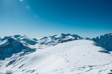 Obraz premium Stunning mountain hill in Bulgaria. Covered with white snow mountain top. Trees are covered under it. Blue skies above. High quality photo