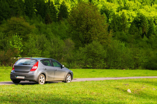 turya, ukraine - MAY 17, 2021: small hatchback in outdoor nature scenery. car on the countryside road through meadow. trees on the near by hill. beautiful springtime landscape in morning light