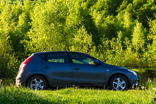 turya, ukraine - MAY 17, 2021: small hatchback in outdoor nature scenery. car on the countryside road through meadow. trees on the near by hill. beautiful springtime landscape in morning light