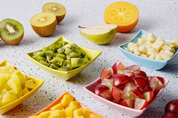 Colorful fruits snacks assortment in small bowls. Raw fresh chopped fruit on a table.