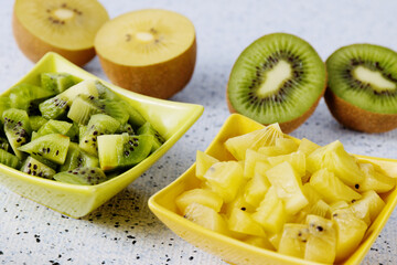 Kiwifruit of different types colors: green kiwi fruit and golden yellow kiwi. Salad cut in bowls.