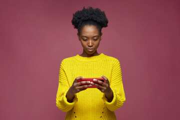Cybersport gamer african american young girl playing mobile game on smart phone on pink studio background © Georgii