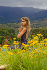 Fototapeta na wymiar Girl with flowers foreground and a landscape behind. Namaste - Hands to your Heart position