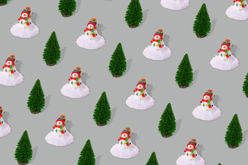 Creative winter pattern made of snowman with snow and pine tree on gray background.