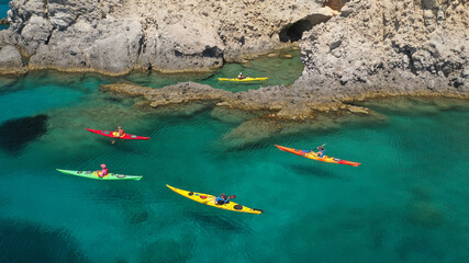 Aerial drone photo of women team of sport kayak in iconic beach and small cove of Tsigrado, Milos island, Cyclades, Greece