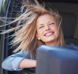 Feel the wind in your hair.... A young woman feeling the breeze in her hair through an open car...
