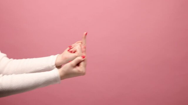 Profile side view closeup of woman hand showing middle finger, impolite rude gesture of disrespect, hate and aggression in conflict. Indoor studio shot isolated on pink background.