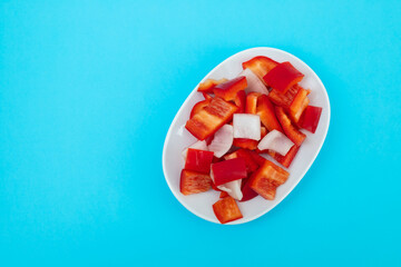 fresh red sweet pepper with onion on white dish