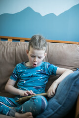 Fototapeta premium boy sitting on a sofa and playing video games