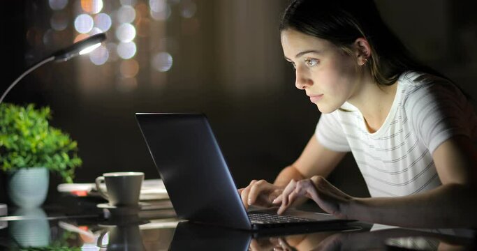 Beautiful woman typing on laptop in the night