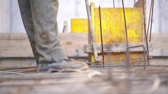 Worker preparing steel poles and bundle wire on steel rod at construction site, close up static 4K
