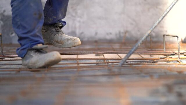 Workers adjusting steel rebars to strengthen building foundation at a construction site, close up static 4K