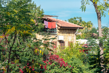 beach towels are drying on the balcony of the attic in a mediterranean town among greenery