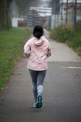 Portrait on back view of asian girl running in a public garden