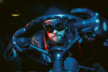 Old school retro image of crazy  driver with beard wearing vintage glasses and leather helmet while...