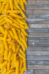 Penne pasts against a wooden grey background 