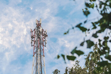 Cell tower against a blue sky with clouds.