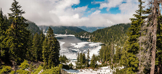A panoramic view of  a snow and ice covered Snow Lake hiking trail