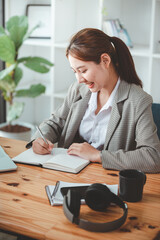 Excited Asian woman sitting at her desk Feel satisfied with the business going well. Very happy to receive letters from laptops and smartphones promoted at work.
