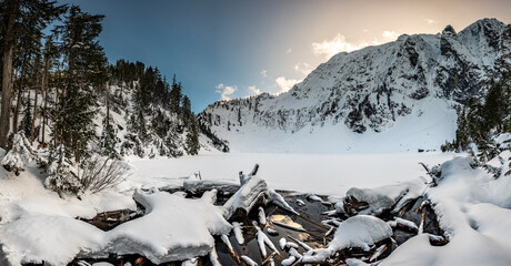 A panoramic view of a snow and ice covered Lake Serene, with snow covered mountains in the background