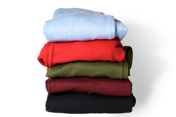 Stack of folded hoodie and hooded sweatshirts on white background. Trendy comfortable casual clothes. Closeup.