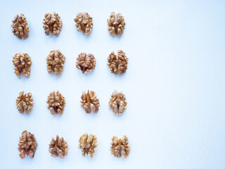 Peeled walnuts lie in a row on a white background