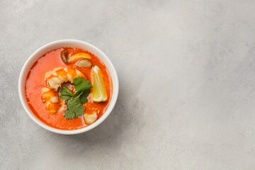 White bowl of fresh Tom Yum soup on a light background