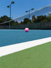 Pink Tennis Ball on Blue Center Court with Black Net - obrazy, fototapety, plakaty