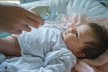 Side view on unknown woman mother using electric baby nasal aspirator mucus nose suction sucking...