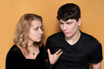 A woman with a serious face criticizes her teenage son, the boy humbly listens to his mother with...