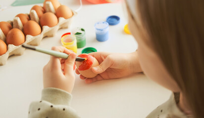 Obraz na płótnie Canvas Little child decorates Easter eggs with colored food paint. Preparing for the feast of the holy Easter.