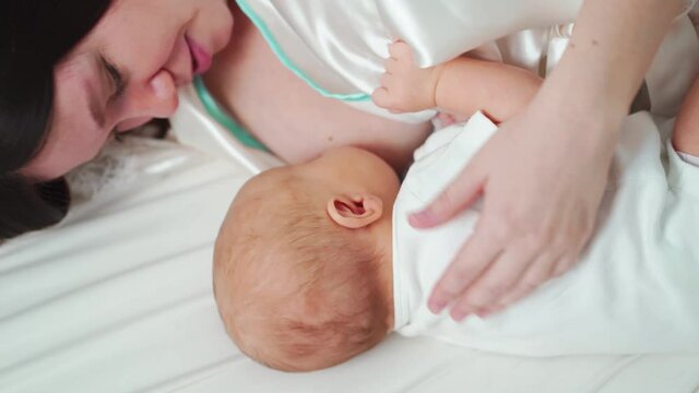 breastfeeding. mother in a bathrobe feeds the baby with breast milk lying in bed