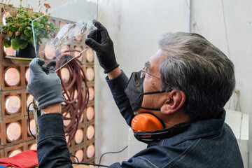 A craftsman checks a piece of glass engraving against the light