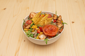 Mexican salad bowl with corn chips, fried chicken, lettuce and cooked rice