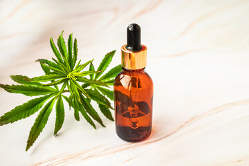 Two bottles CBD Oil in beauty salon. Fresh hemp leaves grown on plantation Marijuana for medical or cosmetic needs. Hemp oil and Green leaves of medicinal cannabis