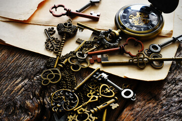 A low angle image of several small brass keys with vintage pocket watch and writing paper.