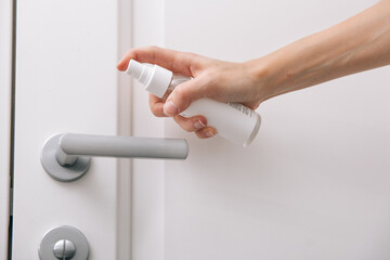 Cleaning white door handles with an antiseptic wet wipe and sanitizer spray. Disinfection in...