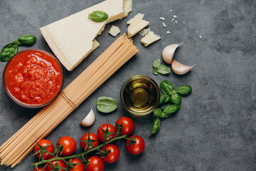 Typical Italian food Pasta spaghetti,  parmesan cheese, olive oil, spices, basil, tomato sauce and fresh tomatoes. top view