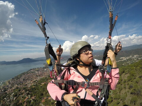 MUJER FEMENINA CON CHAMARRA ROSA HACIENDO SALTO EN PARACAIDASCON SU GO PRO