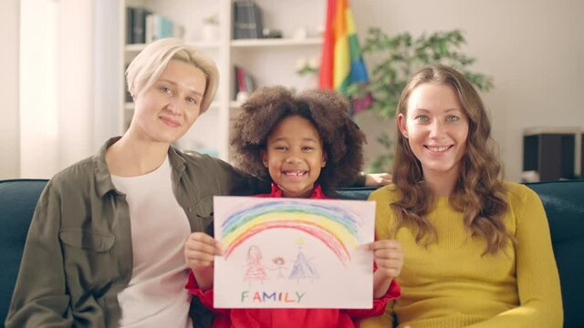 Cheerful adopted girl showing family picture, happy lgbt couple proud of child